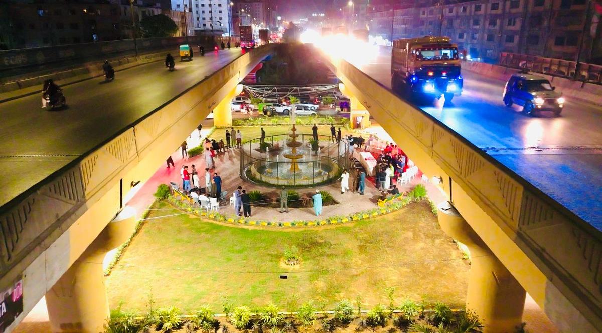 Garden and walkway between two flyover lanes at night