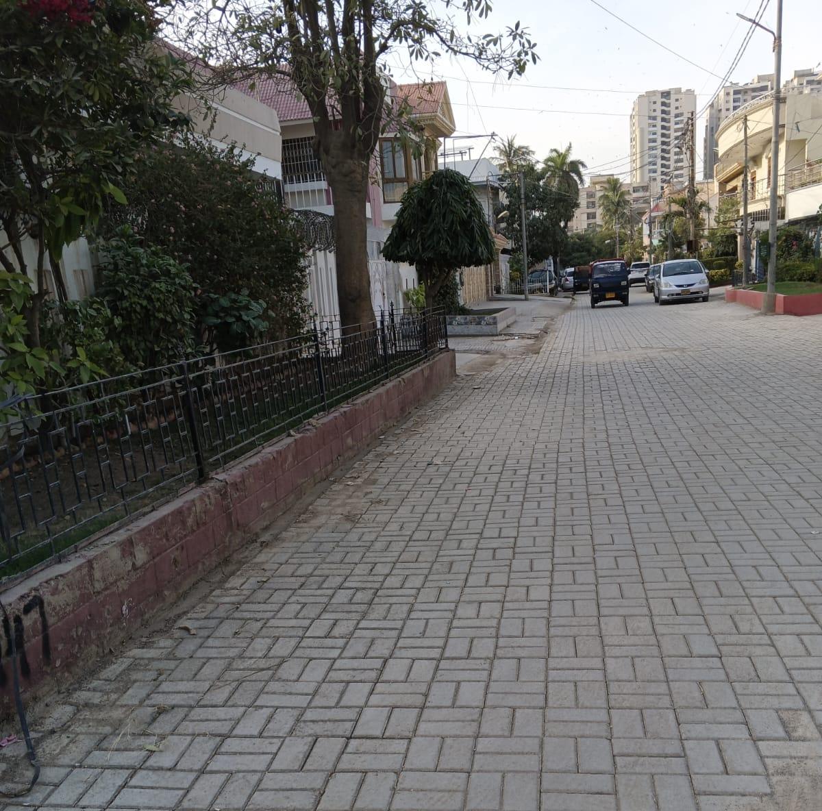 Paver-block road with kerbs and a fenced boundary